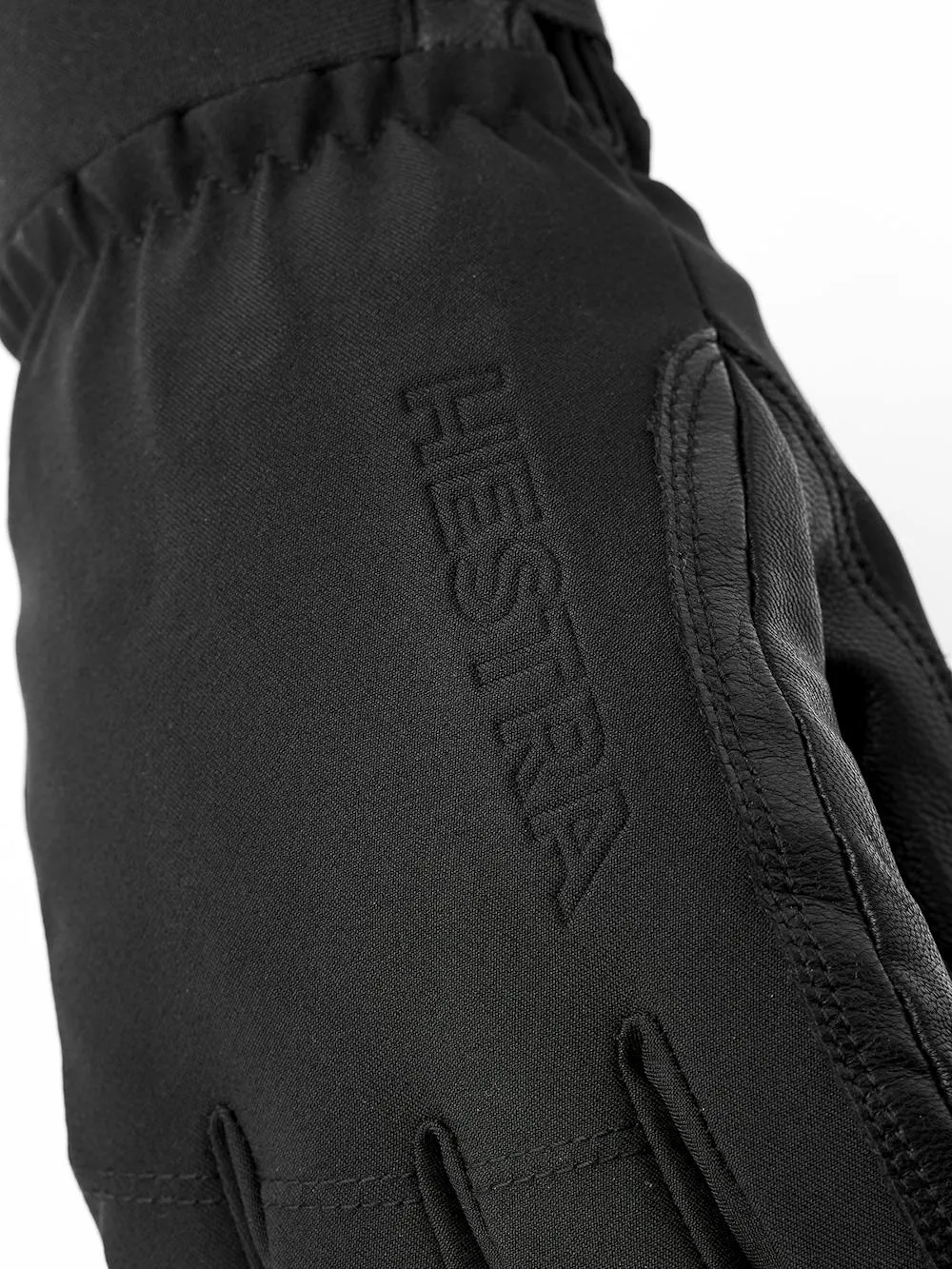 Gros plan sur un gant noir Hestra avec des détails en cuir et le nom de la marque gravé.