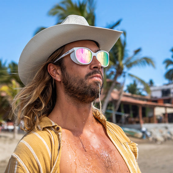 Mann mit Sonnenbrille am Strand Mann mit Hut und Miami Nights Sonnenbrille, nassem Gesicht und Hemd, im Hintergrund Strand und Palmen.