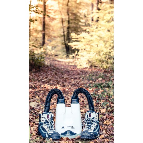 Alpenheat UniversalDry shoe dryer with two hiking boots in the fall leaves in front of a forest path.