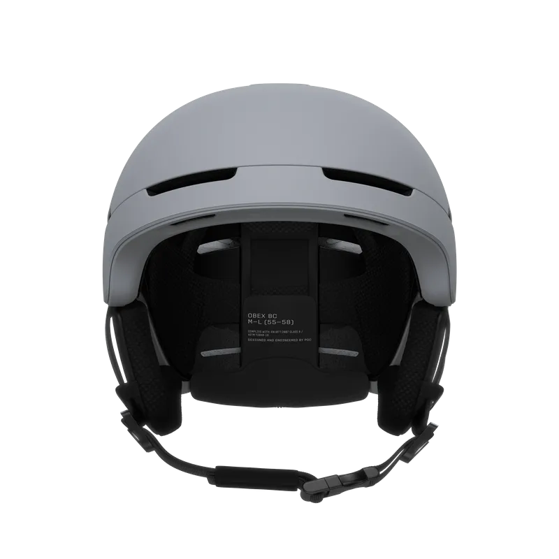 Grauer Skihelm von vorne, mit Belüftungsöffnungen, Ohrenschützern und verstellbarem Kinnriemen. Innen Mesh-Polsterung.
