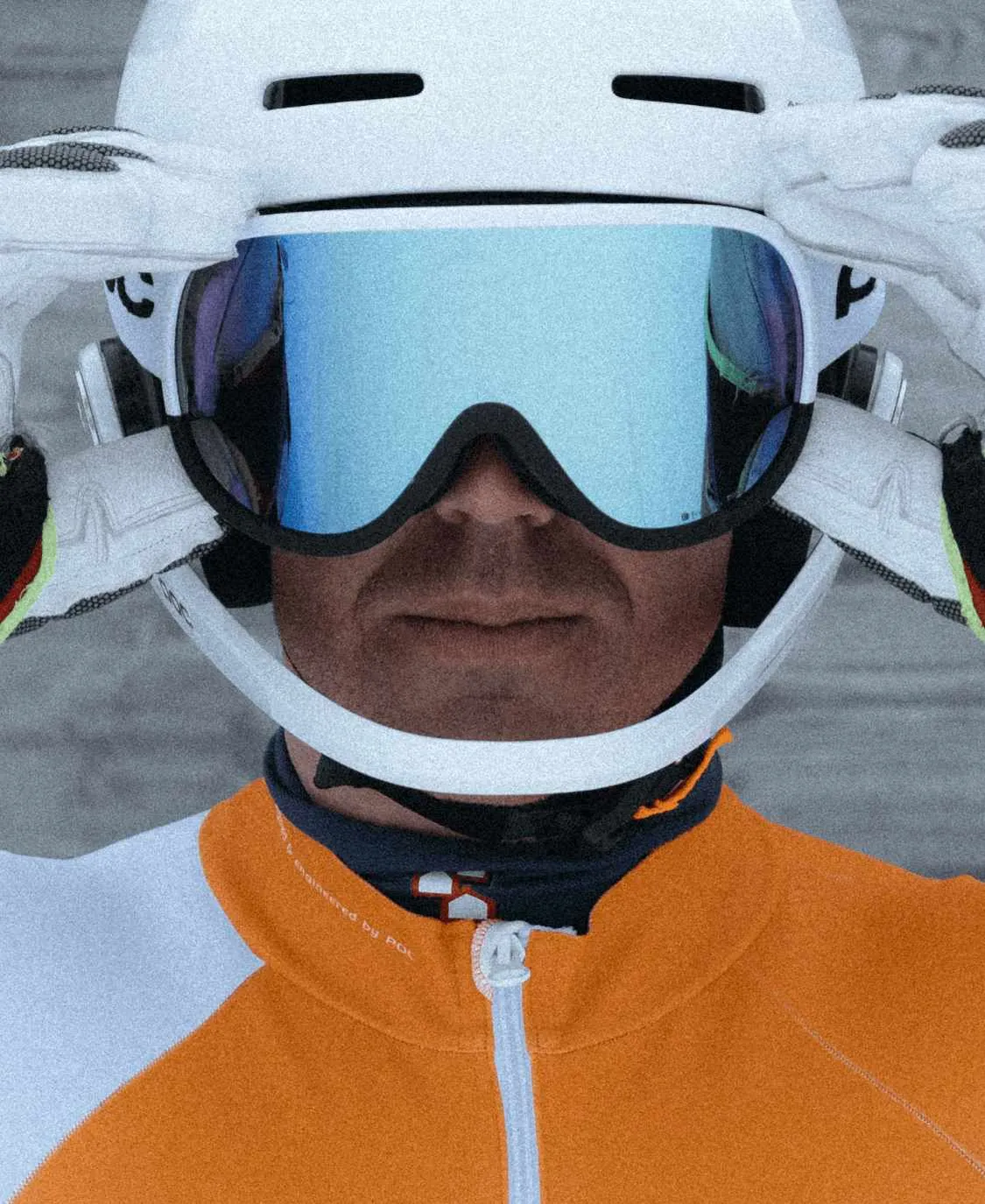Sciatore con casco e occhiali da sci POC Retina Race con lenti blu, mani che regolano gli occhiali.