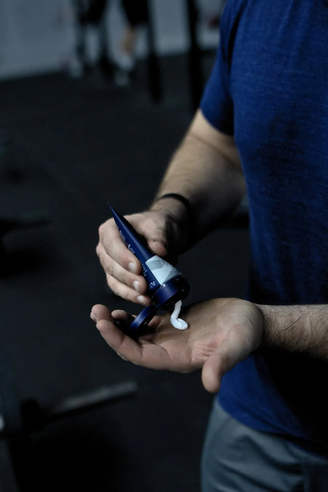 Uomo che tiene in mano SPORT LAVIT Super Grip. Tubo blu e bianco con crema bianca.