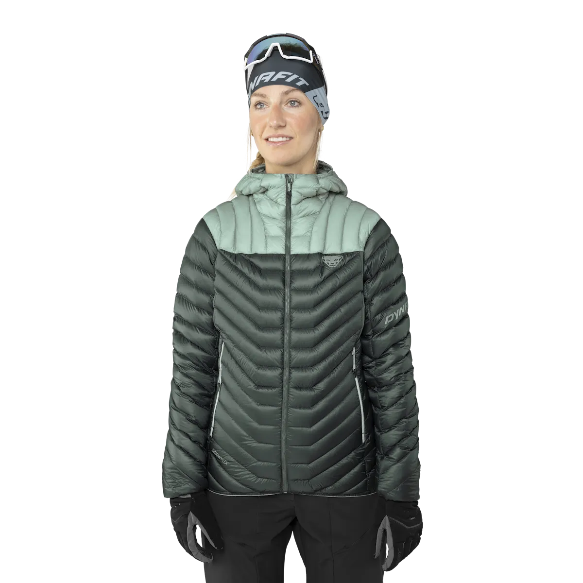 Woman in down jacket with hood, green and gray, wearing headband and gloves.
