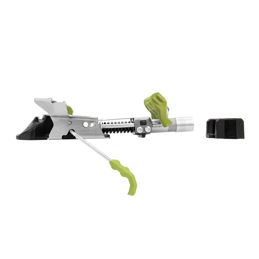Partie talonnière d'une fixation de ski de randonnée en métal argenté et en plastique noir et vert vif. Avec mécanisme de réglage à ressort, plusieurs leviers verts et étrier latéral. À droite, un petit bloc noir.