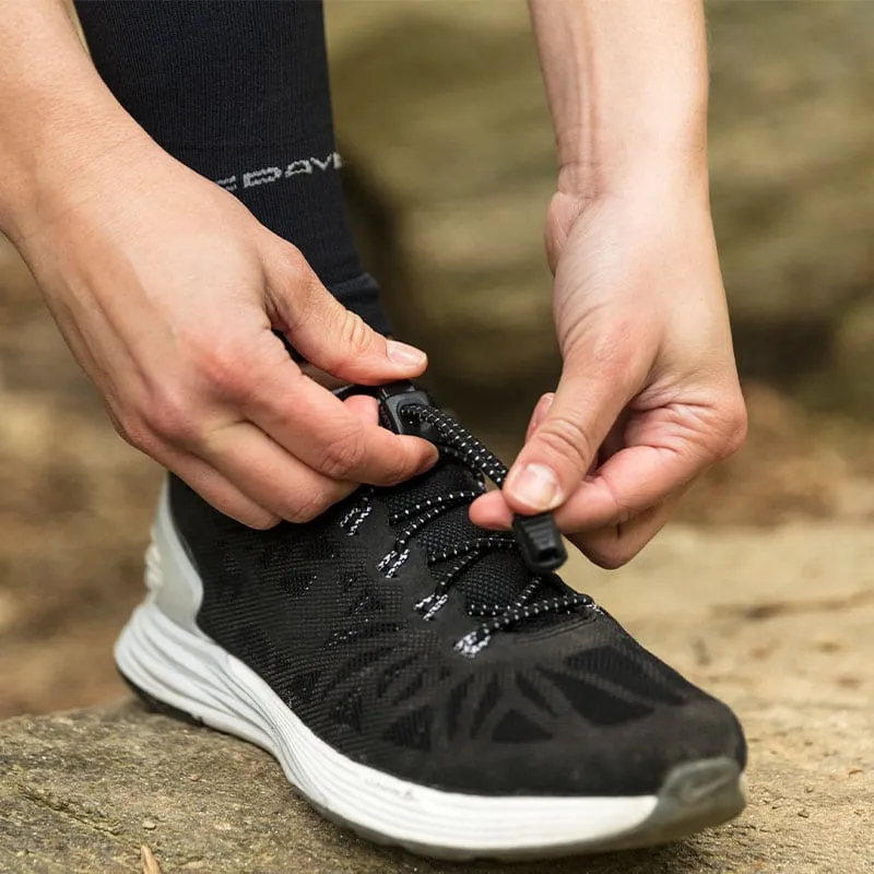 Two hands operate a Run Laces lacing system on a black running shoe.