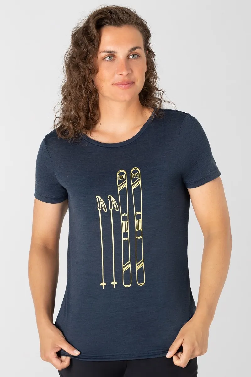 Frau trägt ein blaues Skiing Tee mit goldenem Ski- und Stock-Print.