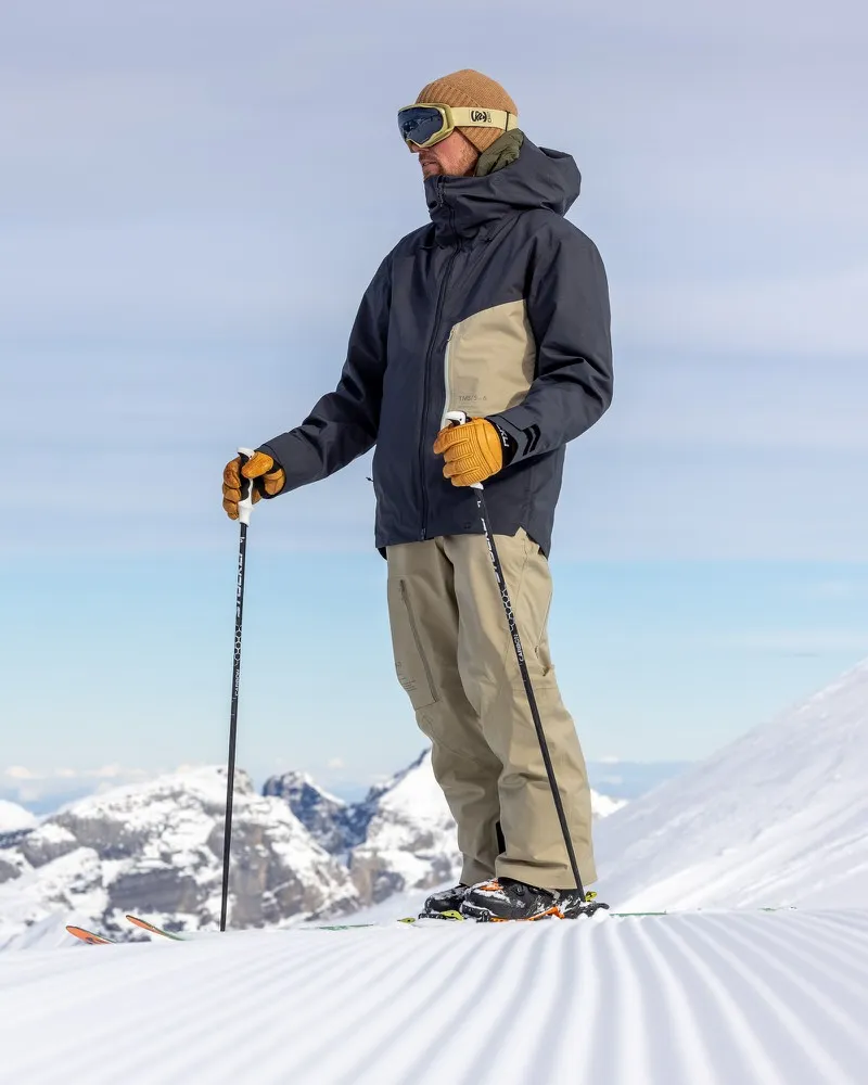 A man with ski goggles and cap wears the S-6 Ride Insulated Jacket Asphalt Seneca Rock while skiing.