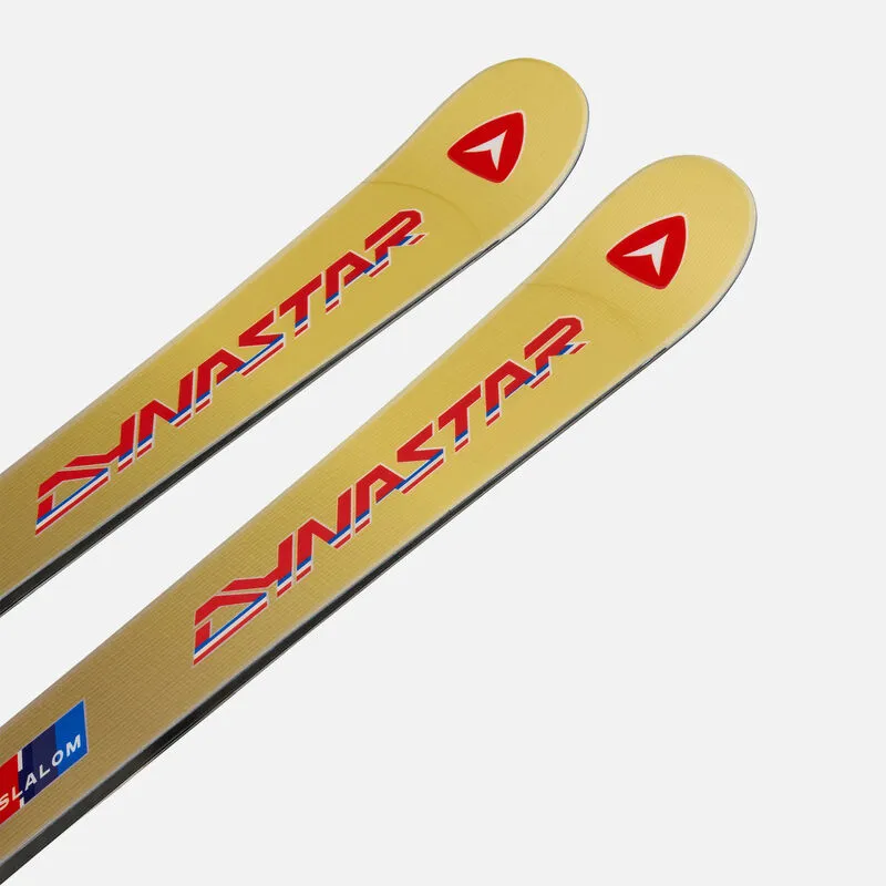 Two gold-colored Dynastar slalom skis, arranged diagonally, with red logo and lettering.