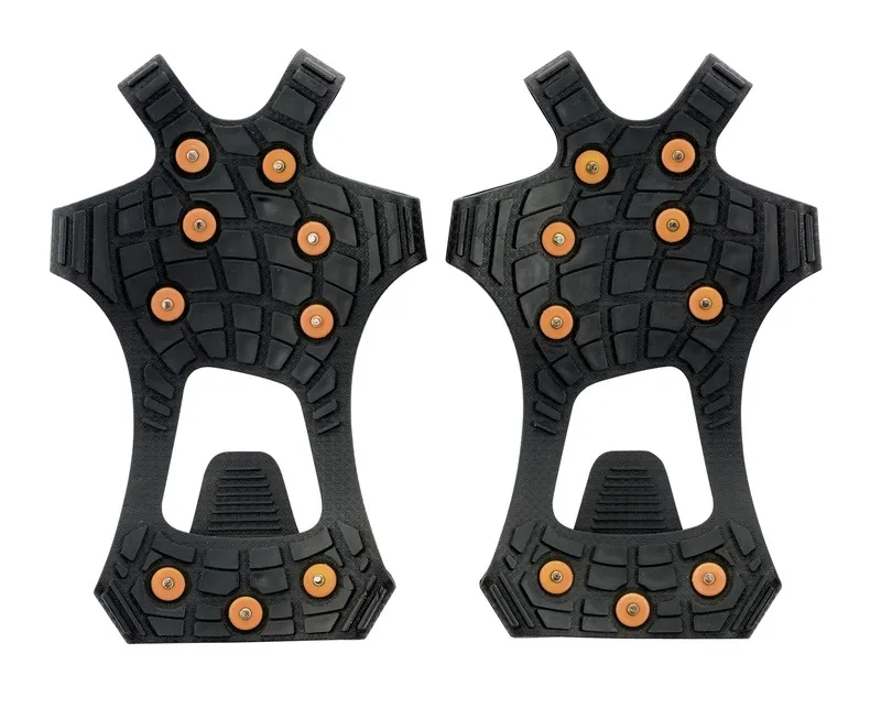 Two black Sidas Walk Traction shoe claws with spikes lie next to each other against a white background.