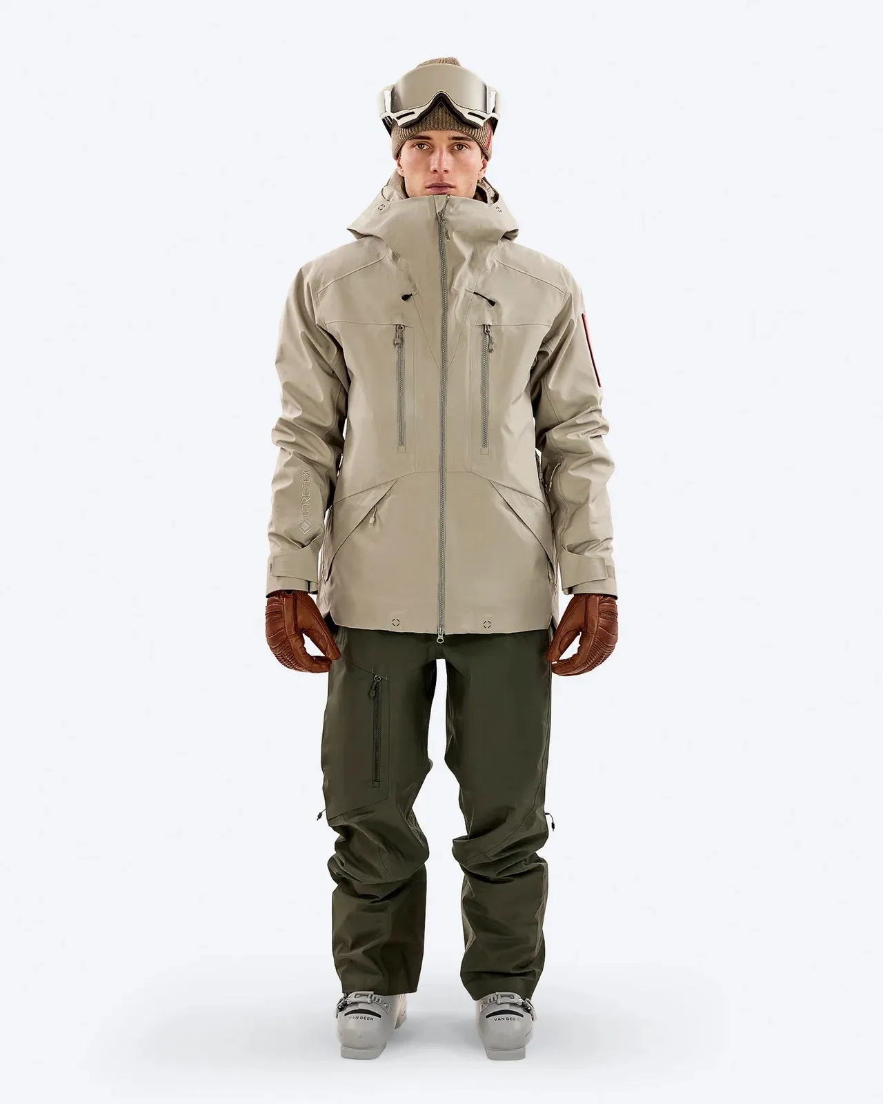 Model with Z-2 EPE 3L Jacket Seneca Skirt, ski goggles and gloves. The jacket is beige, the pants are green.