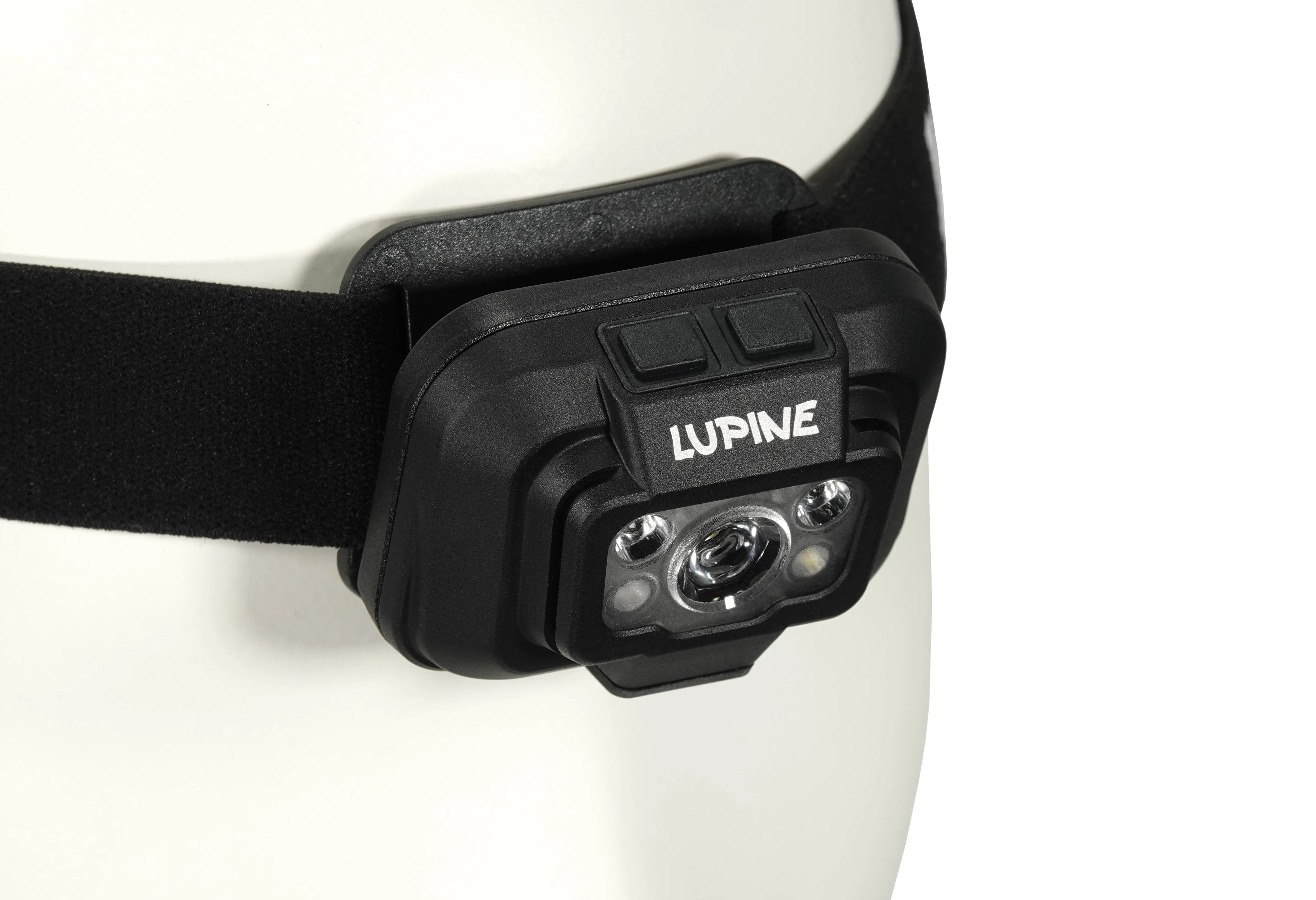 Gros plan d'une lampe frontale Penta avec un bandeau noir sur une tête blanche. Inscription "Lupine".