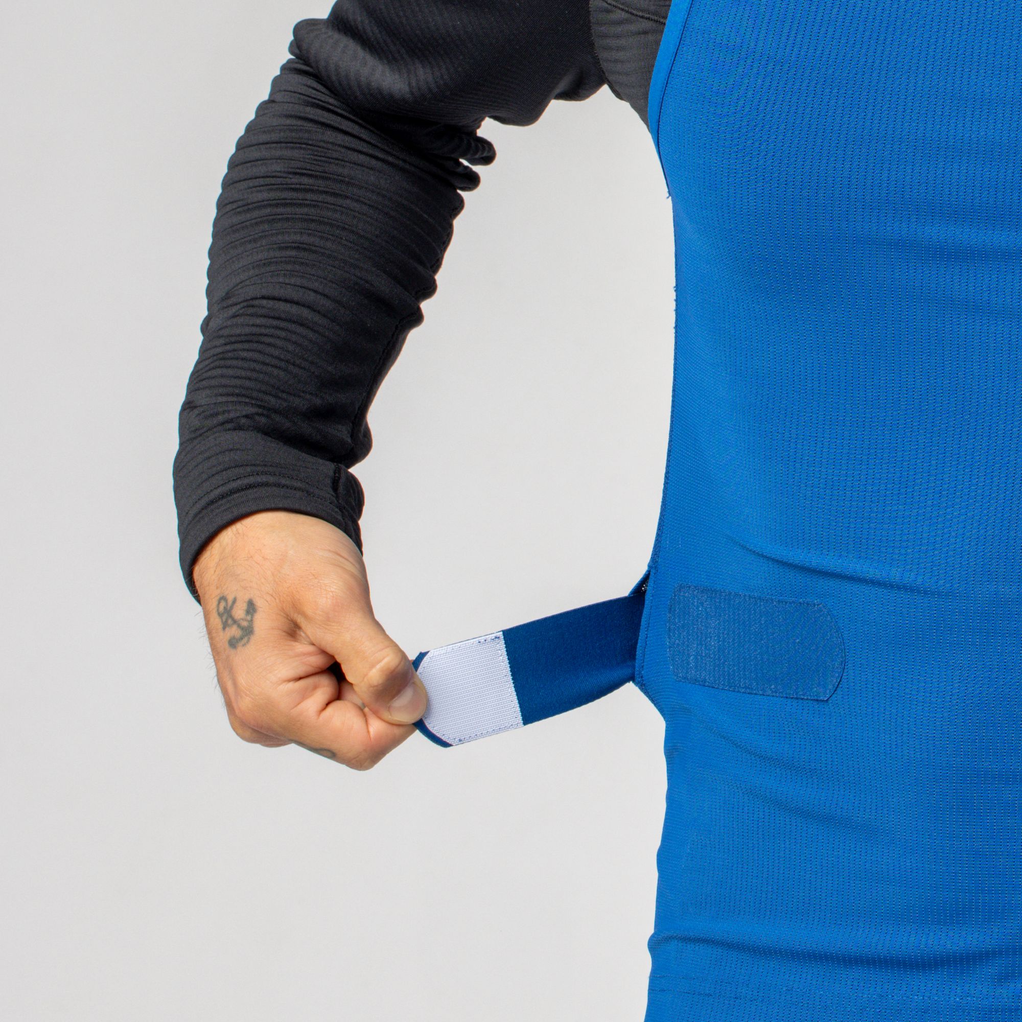 Regolazione della protezione da uomo Un uomo regola il protettore da uomo Scott Airflow blu regolando la cintura sul fianco con il velcro.