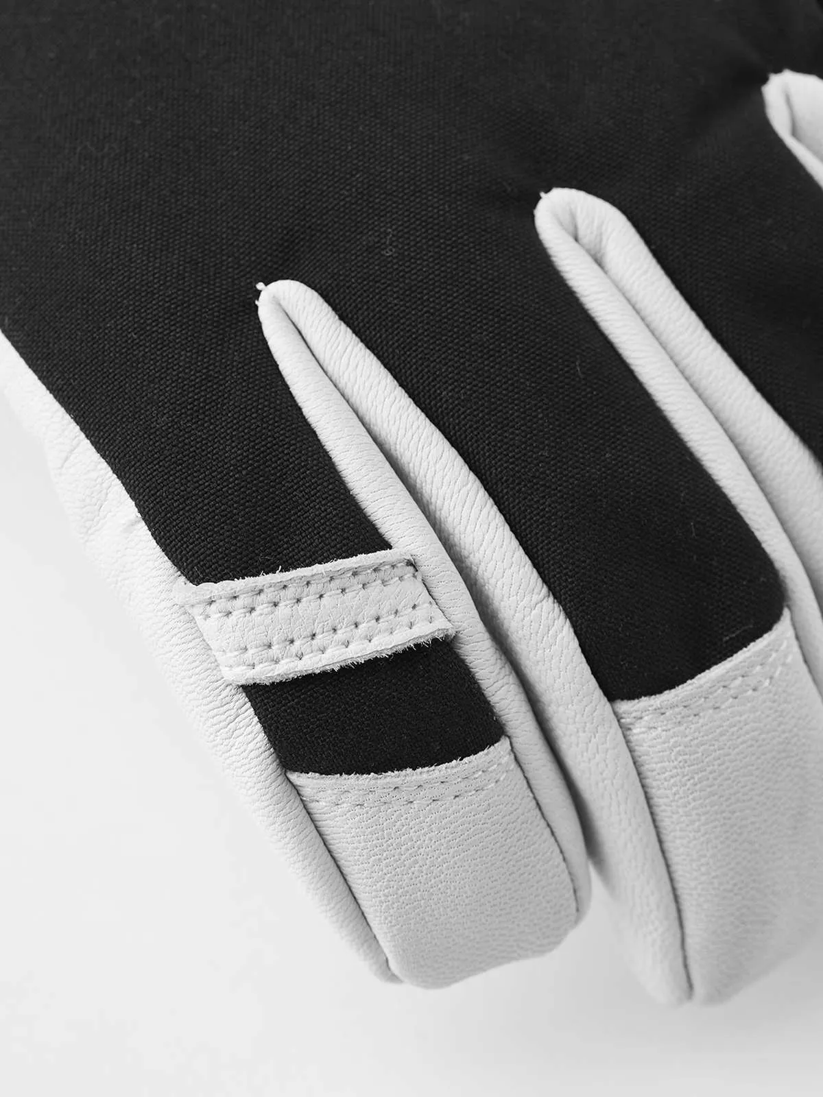Detailaufnahme eines schwarzen/grauen Hestra Army Leather Heli Ski Mitt Handschuhs. Die Finger sind hellgrau und der Handrücken ist schwarz.