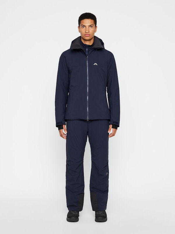 Ein Mann trägt navyfarbene J.Lindeberg Truulli Skihose und passende Jacke.