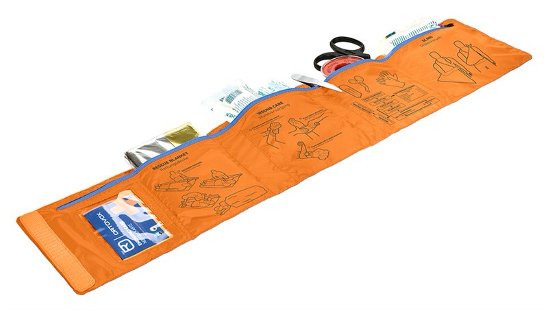 Ausgerolltes, orangefarbenes First Aid Roll Doc Set mit Rettungsdecke, Schere, Verbänden und einer Notfallkarte von Ortovox.