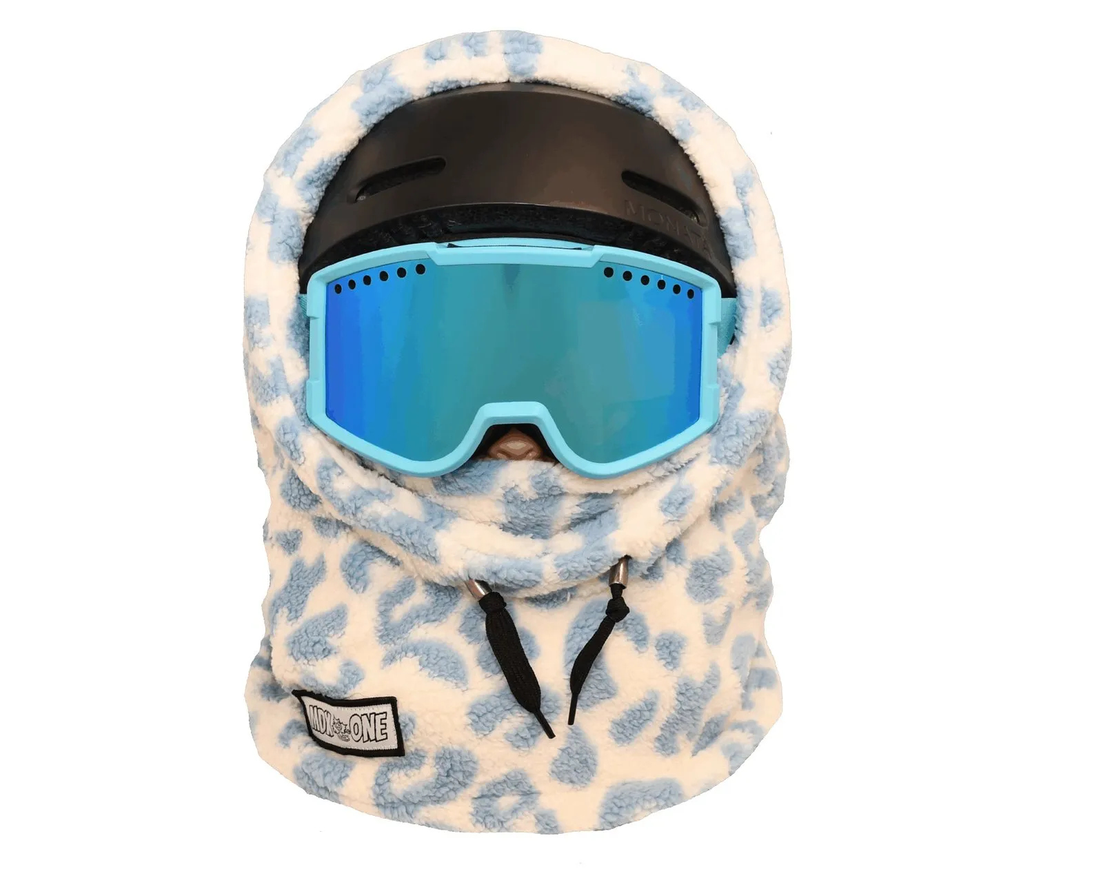Flauschige, cremefarbene Balaclava mit blauen Giraffenflecken, über schwarzem Skihelm. Hellblaue Skibrille mit verspiegelten Gläsern bedeckt den Bereich bis zur Nase. Weicher Stoff schützt Kopf und Hals. Zwei schwarze Kordelzüge unten.