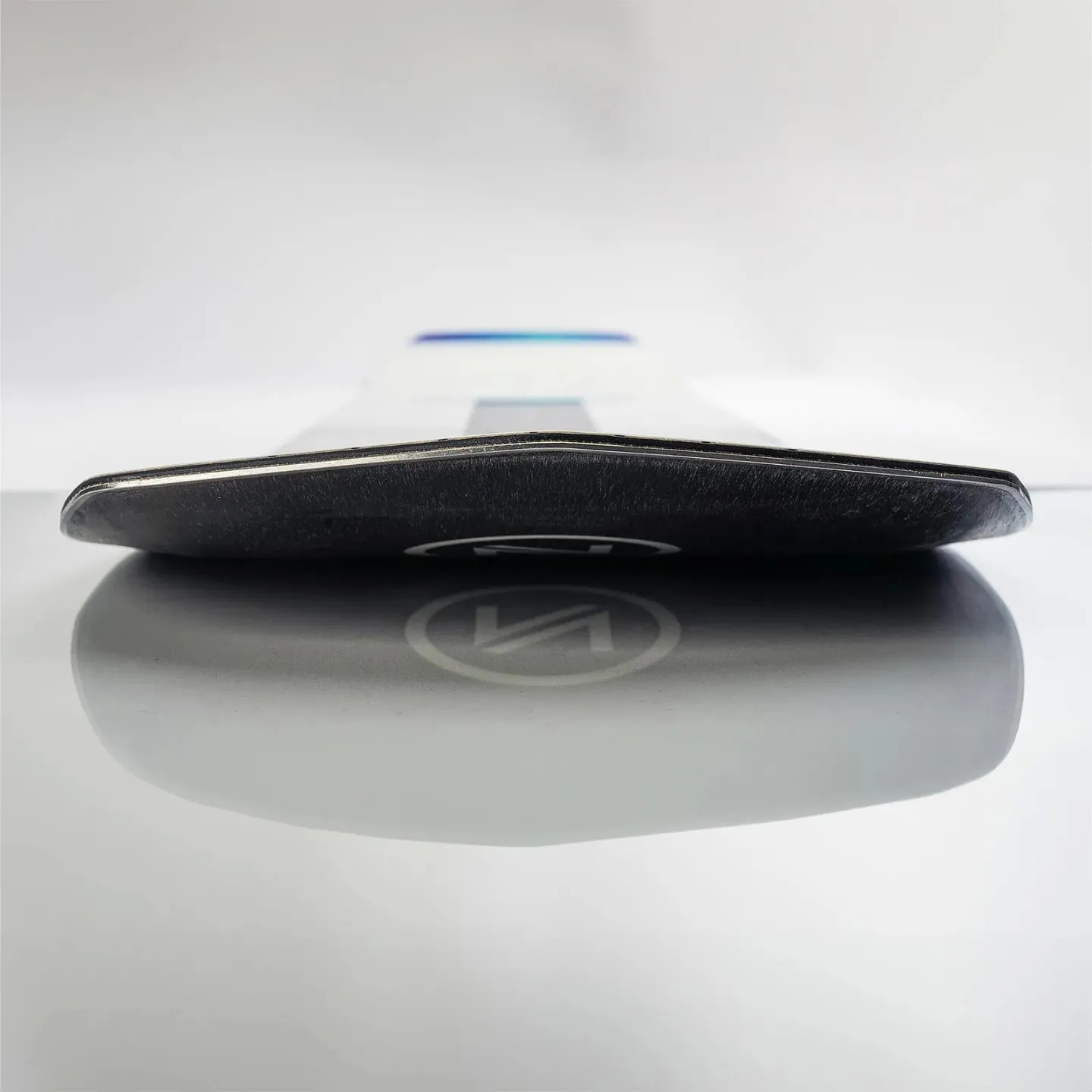 Gros plan sur le snowboard Nidecker Thruster, focus sur la carre et le logo qui se reflète sur la surface.