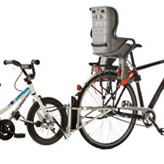 Tandemkupplung: Kinderfahrrad an Erwachsenenfahrrad gekoppelt. Am Erwachsenenfahrrad ist ein Kindersitz befestigt.