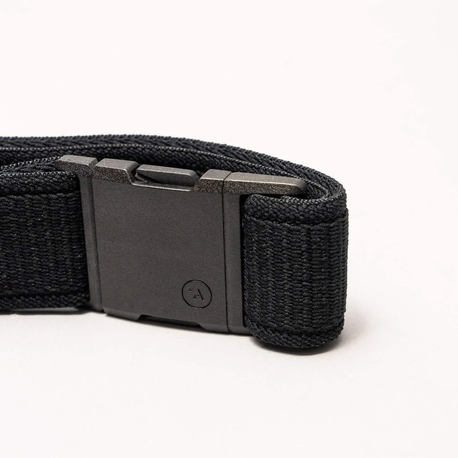 Gros plan sur la ceinture Arcade Atlas en noir. Bande élastique tissée avec boucle plate en plastique noir sur fond blanc.