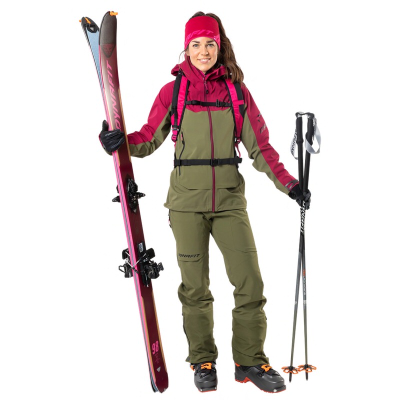 Femme en Beet Red Dynafit Veste hybride Beast, skis et bâtons, prête pour la randonnée à ski.