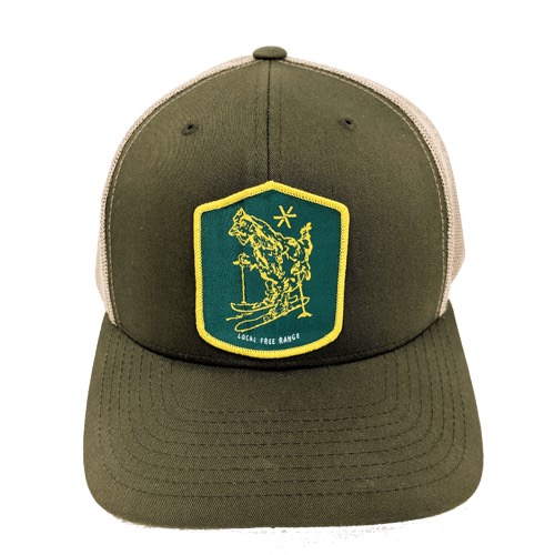 Casquette de ski verte Casquette verte avec écusson jaune représentant un skieur avec le texte "Local Free Range".