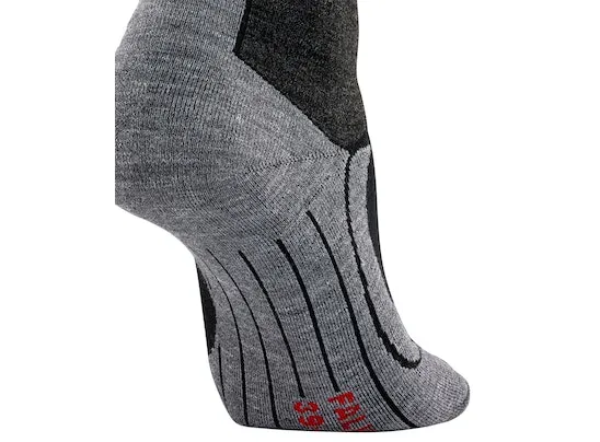 Detailaufnahme eines grauen FALKE SK4 Skistrumpfs mit schwarzen Verstärkungen und roten Schriftzug am Fuß.
