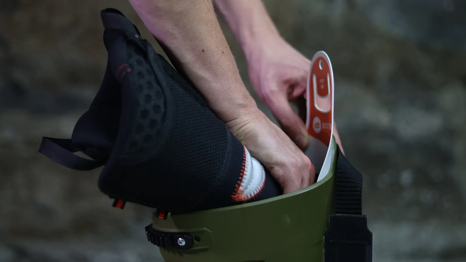 Close-up of hands inserting a save liner into a green boat. The liner is black with white details.