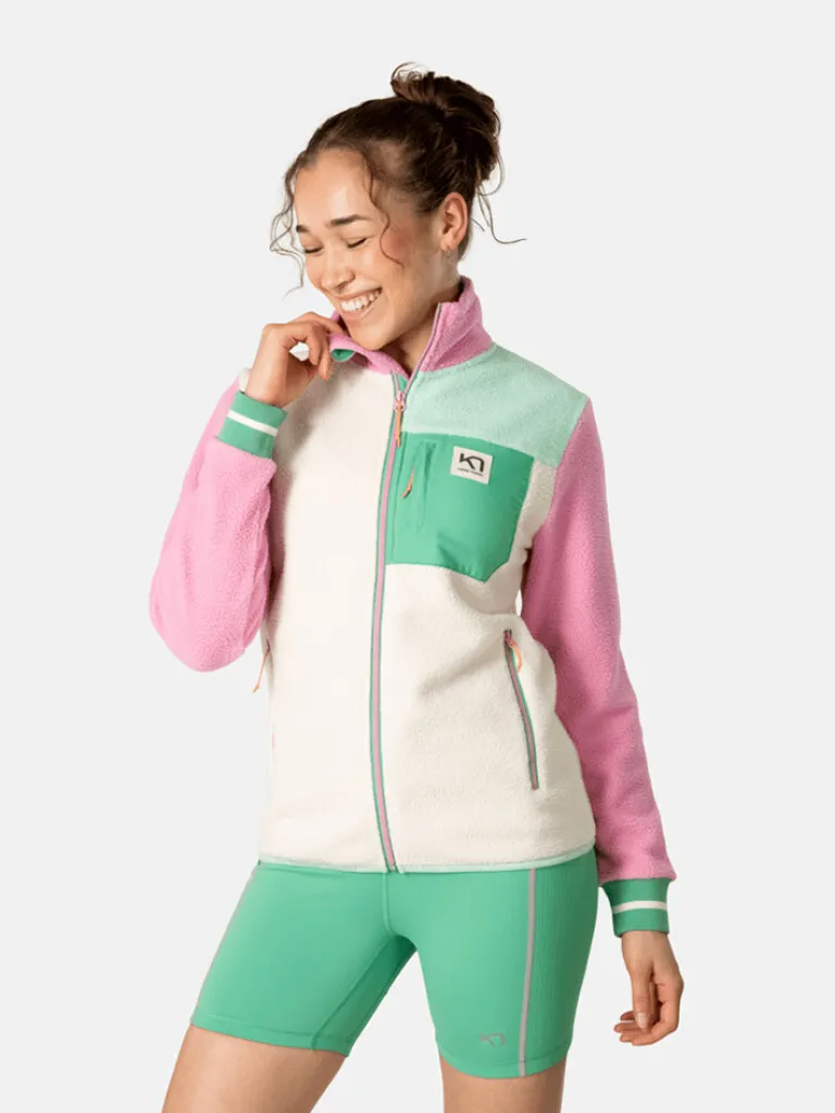 Smiling woman wears Kari Traa Rothe midlayer in white, pink and green, with matching shorts.