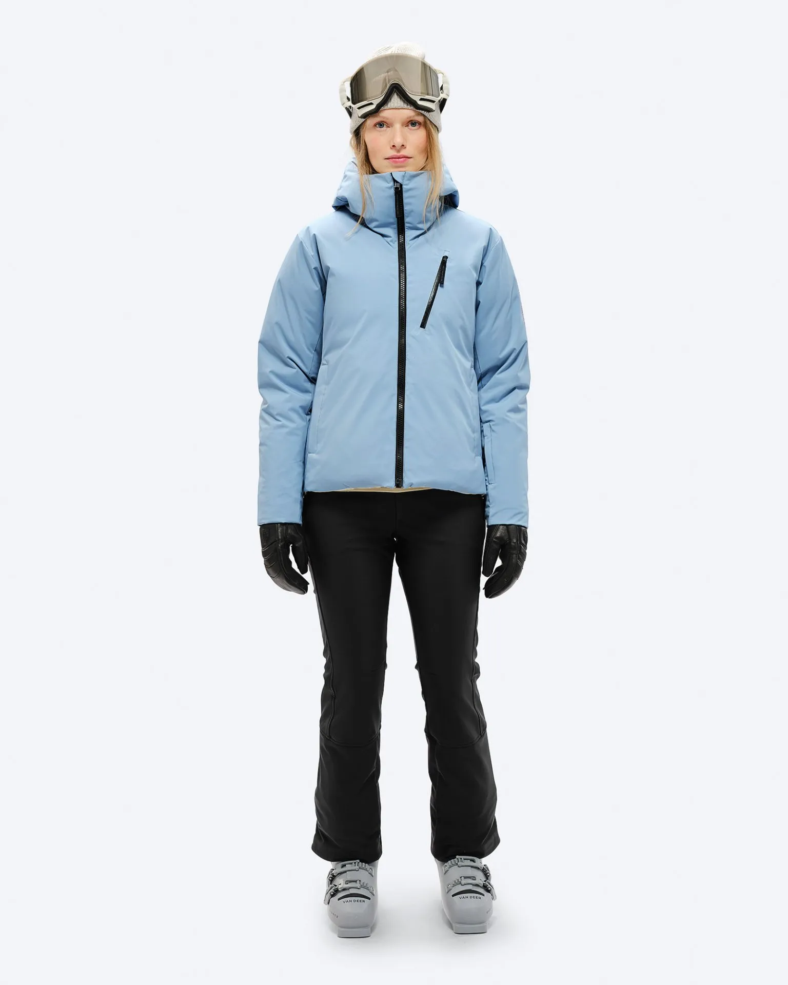Person mit Skibrille, Daunenjacke in "Castle Wall", schwarzer Hose und Handschuhen, sowie Skischuhen.