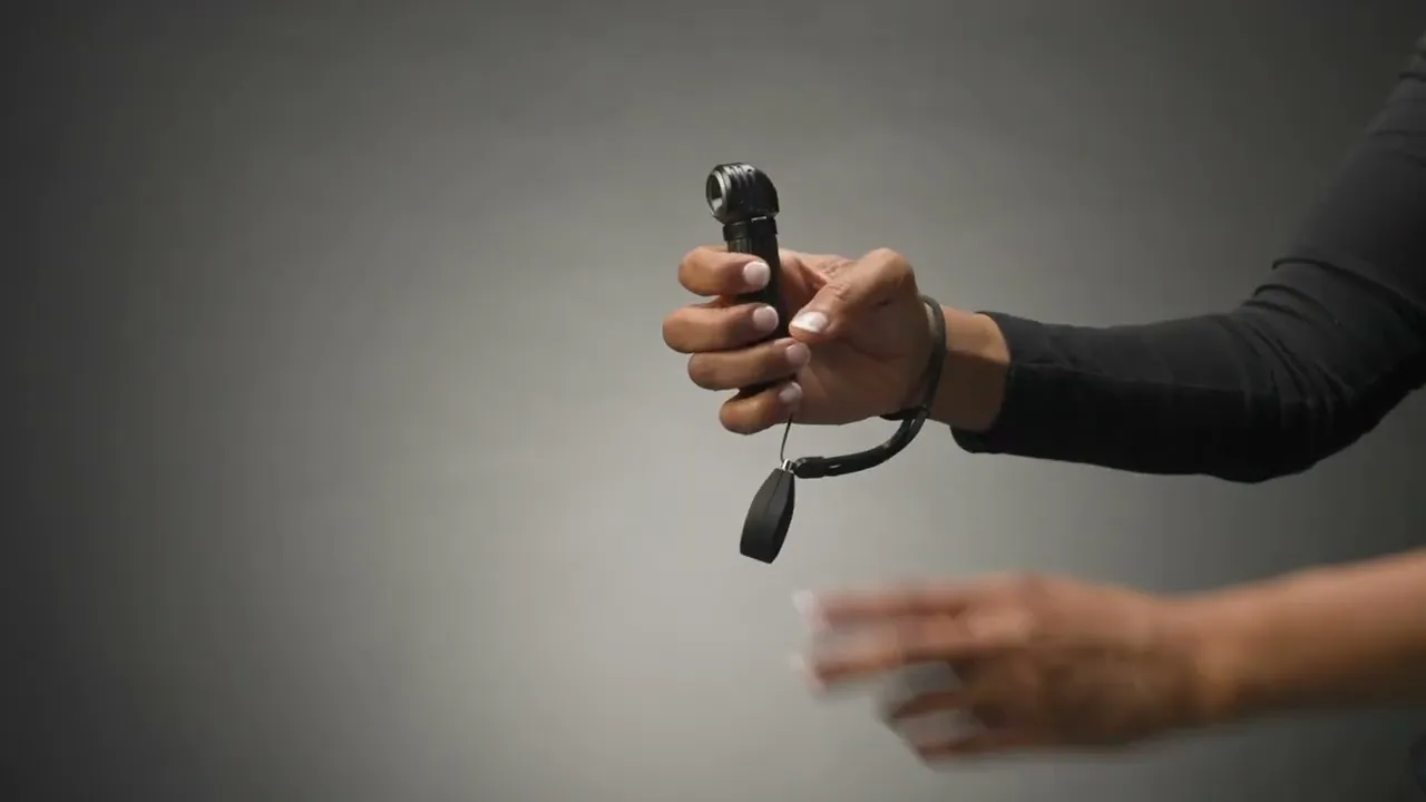 Eine Hand hält die Suprabeam M6xr BodyGuard Taschenlampe. Am Handgelenk ist ein Trageband befestigt.