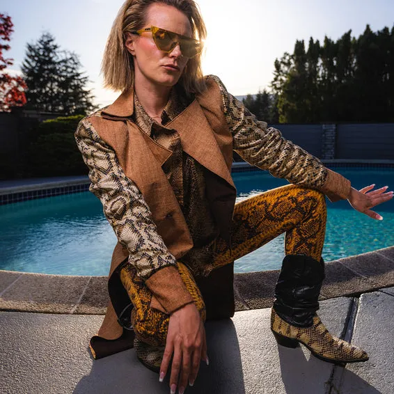 Model mit Sonnenbrille und Pyrit-Musterkleidung posiert vor einem Pool.