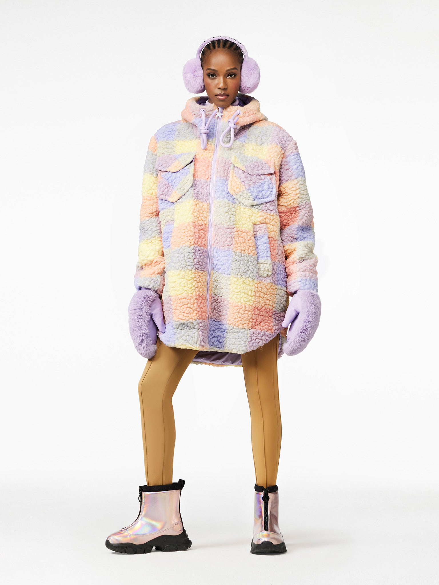 Model mit CHAD JACKET in Pastell-Lammfelloptik, passenden Ohrenwärmern und Handschuhen, kombiniert mit Leggings und schimmernden Boots.