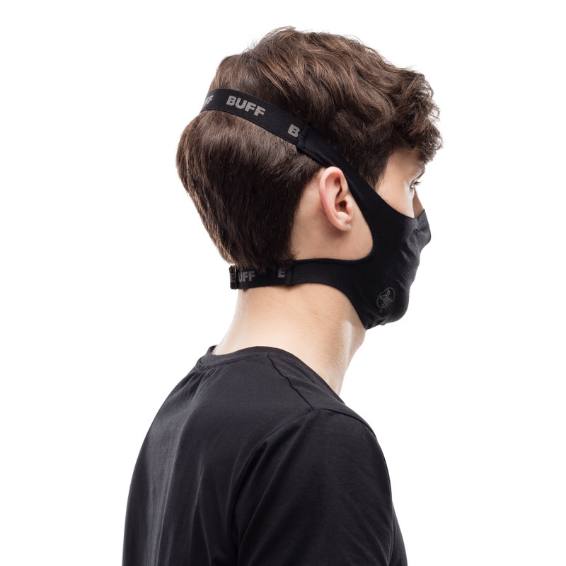 Person trägt eine schwarze Buff Filter Maske, Ansicht von der Seite. Die Maske wird mit Bändern gehalten.