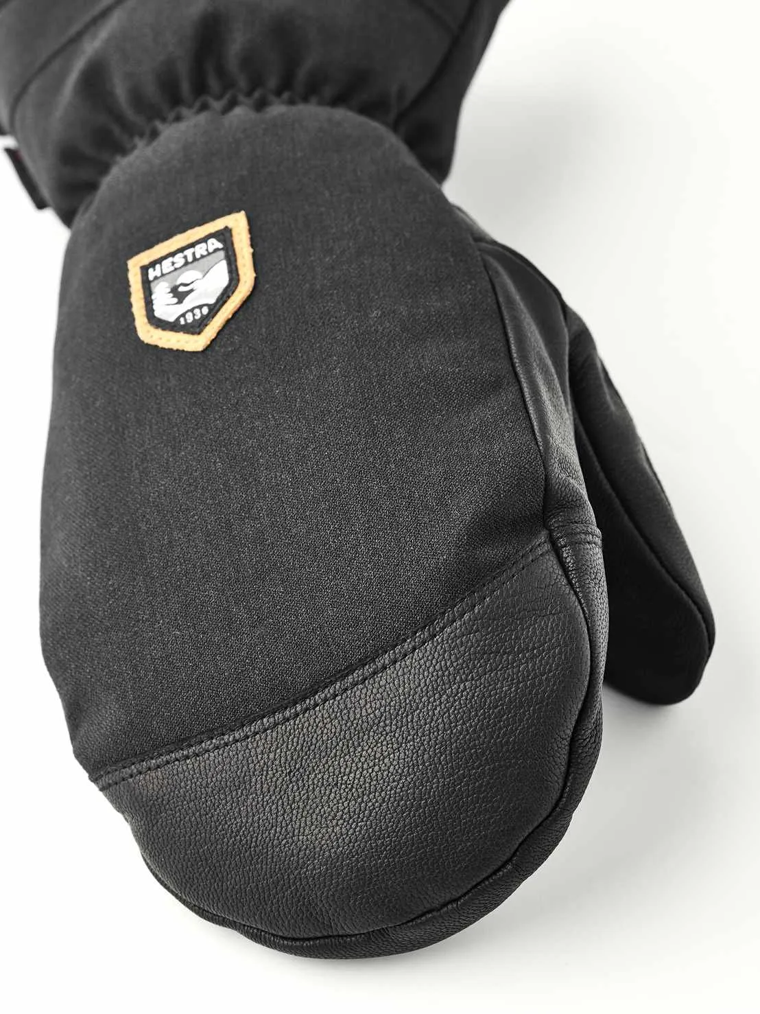 Gros plan sur une moufle noire en tissu et cuir avec le logo Hestra.