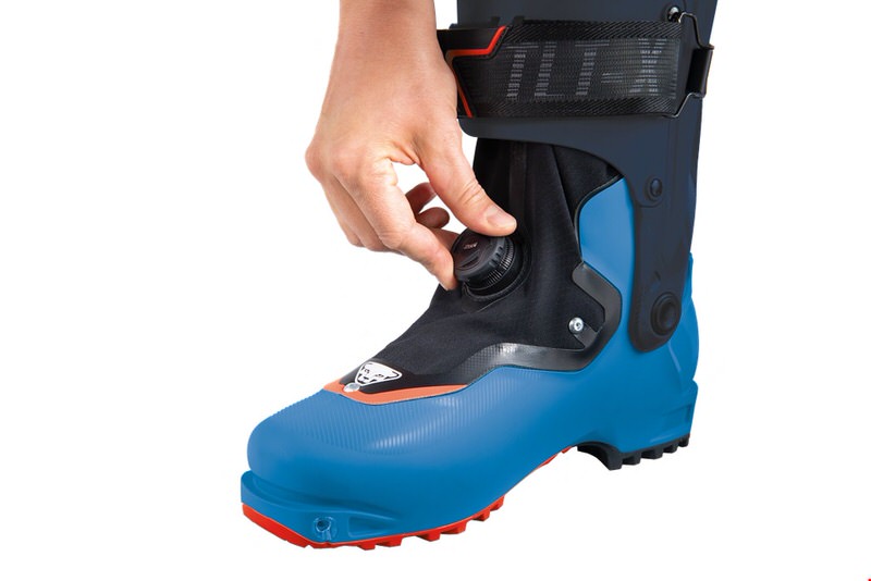 Ein blauer Dynafit TLT X Boot wird mit einer Hand am Drehverschluss eingestellt.