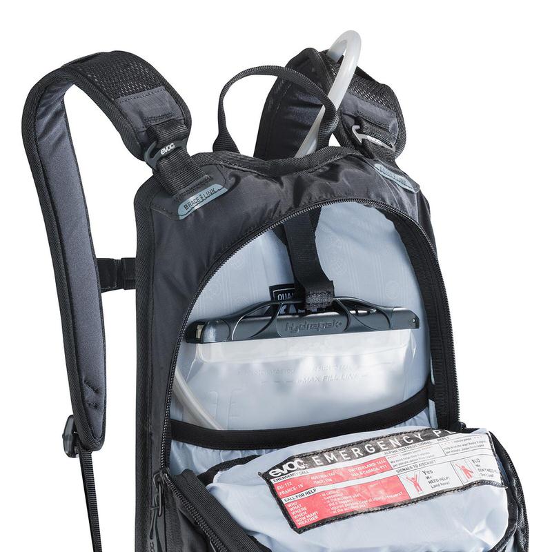 Schwarzer Evoc Stage 6l Rucksack, offen, mit 2l Trinkblase von Hydrapak und Notfallhinweisen.