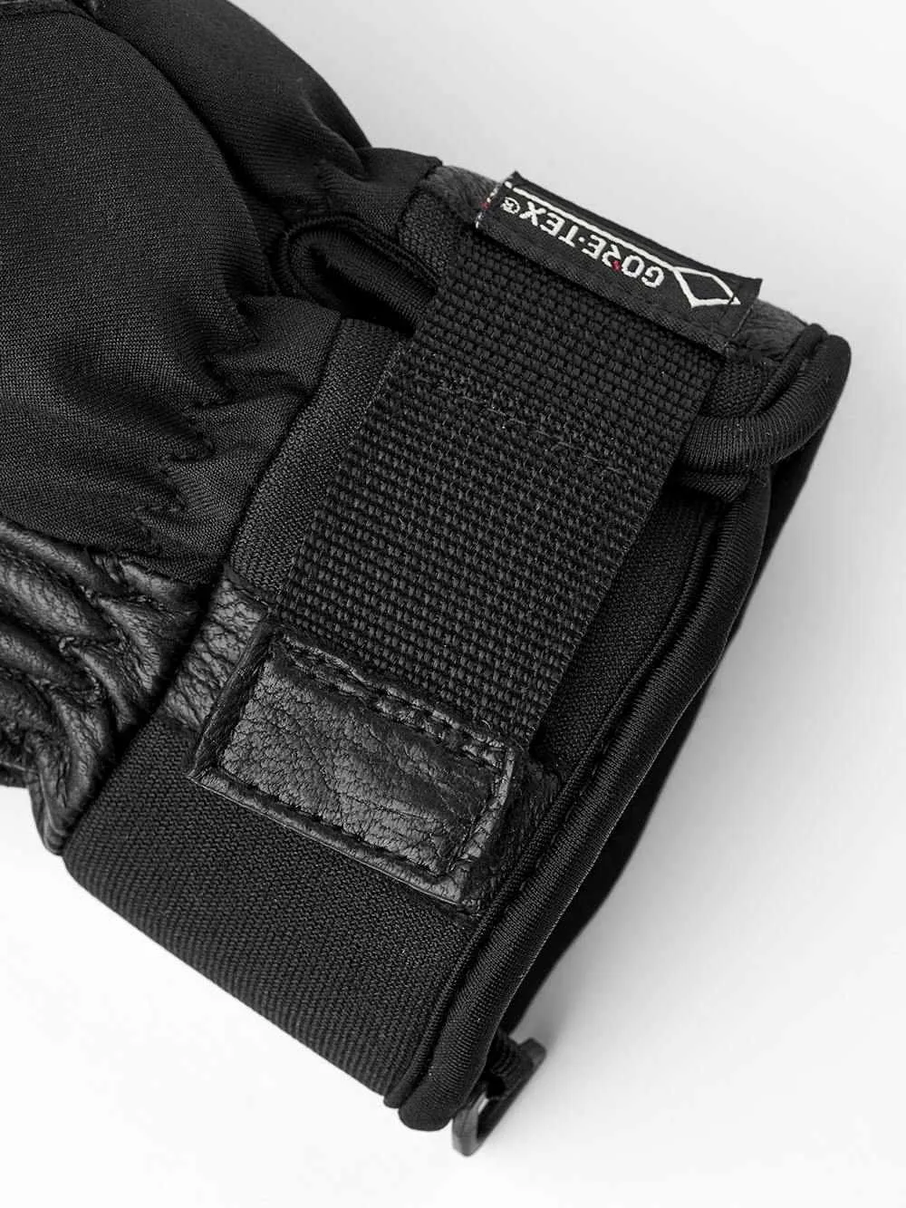 Détail d'un gant noir avec des détails en cuir et une étiquette GORE-TEX®.