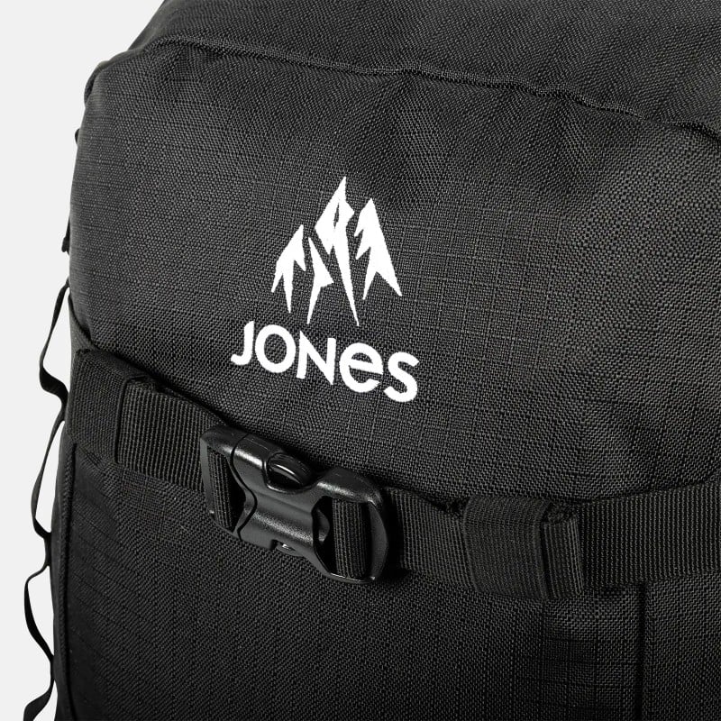 Detailaufnahme des schwarzen Jones Deeper 19L Backpack mit weißem Logo und schwarzem Gurtverschluss.
