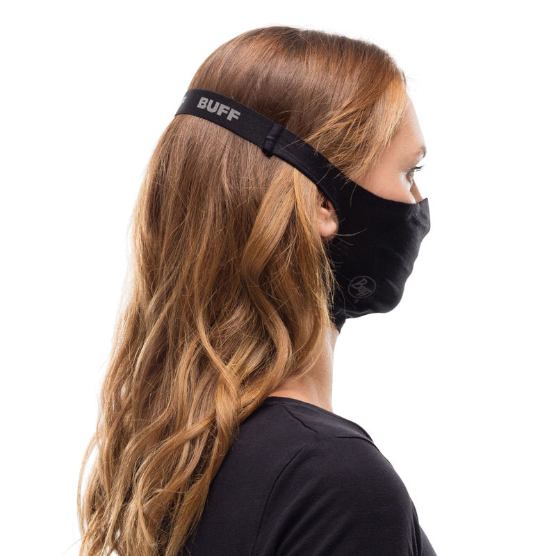 Profilansicht einer Person mit langer, gewellter, brauner Haare, die eine schwarze Buff Filter Maske trägt.