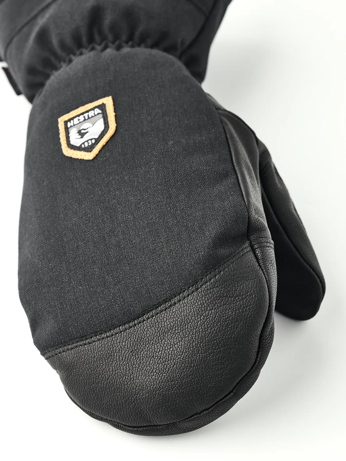 Gros plan sur une moufle noire en tissu et cuir avec le logo Hestra.
