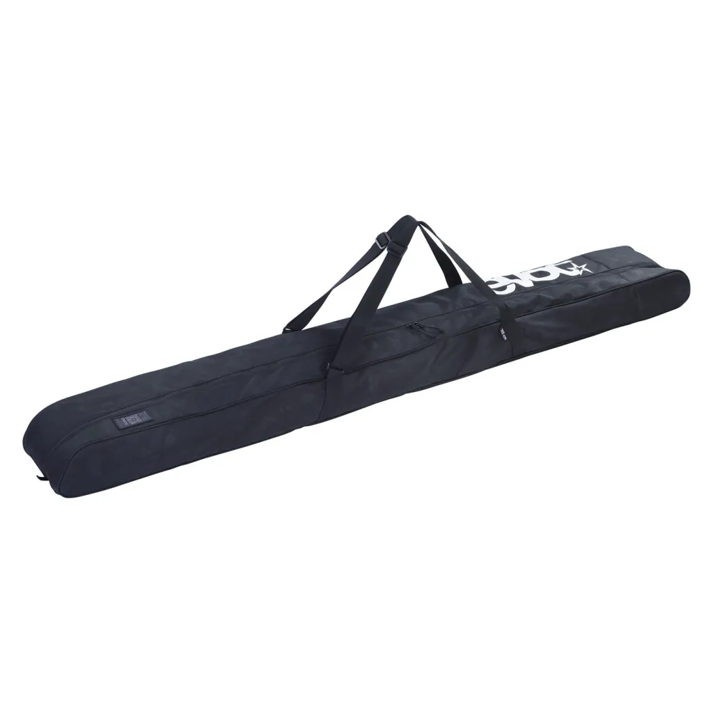 A long, black ski bag lies diagonally in the picture, with two carrying straps and a white logo at the top.