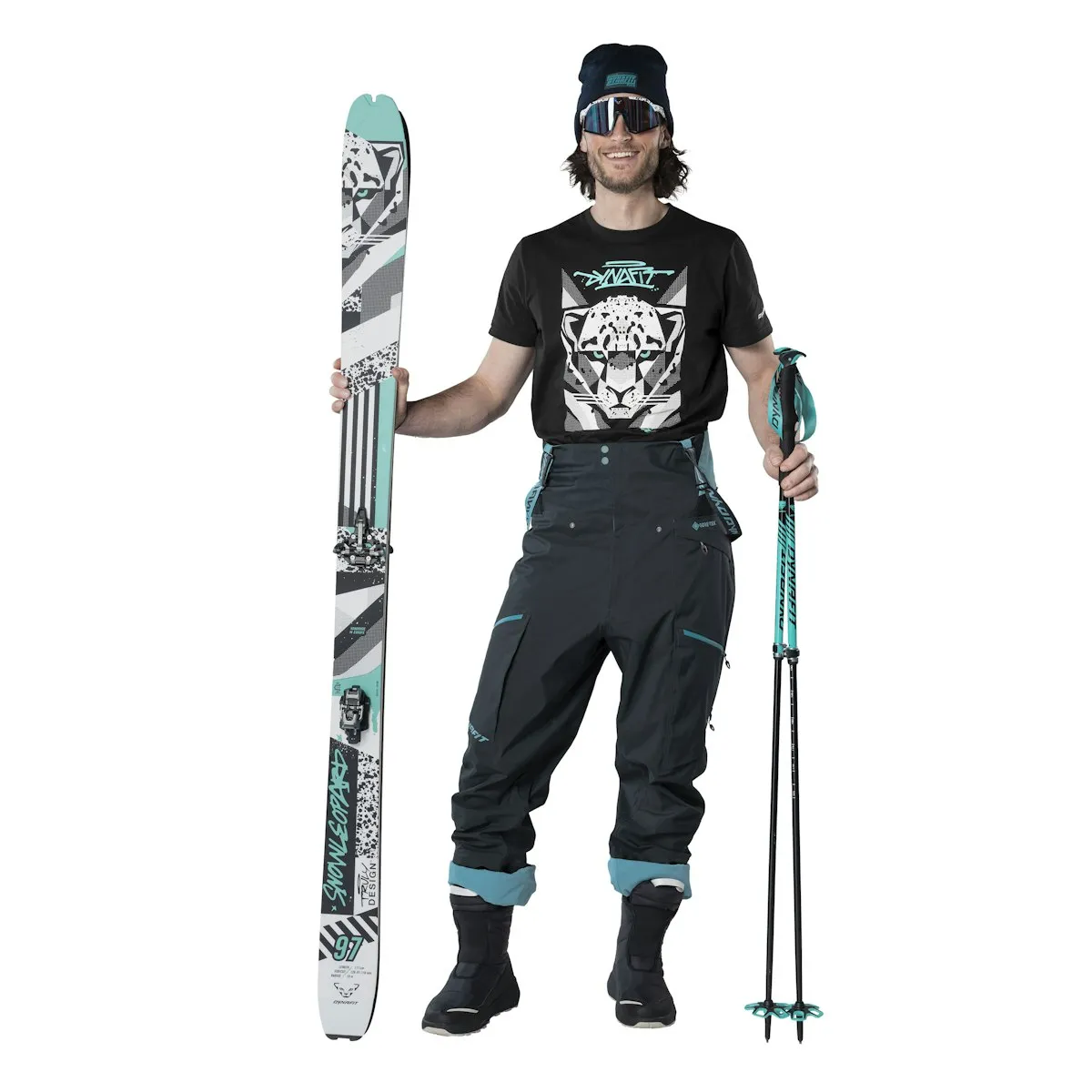 Ski outfit: Man with skis, ski poles, cap, goggles and T-shirt with leopard motif. Dark ski pants.