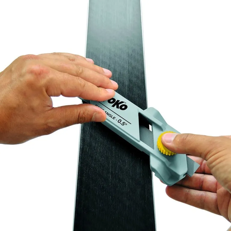 Ski edge grinder "Toko Express Base Angle 0.5°" in use on skis. Hands hold the tool in place.