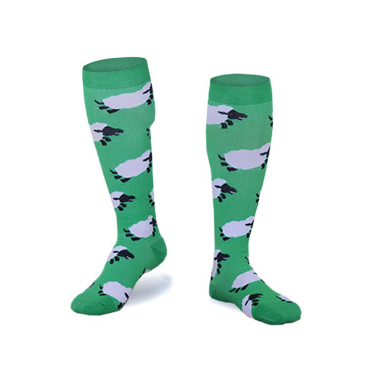 Grüne Skisocken mit Schafmuster, dargestellt auf zwei einzelnen Socken vor einem weißen Hintergrund.