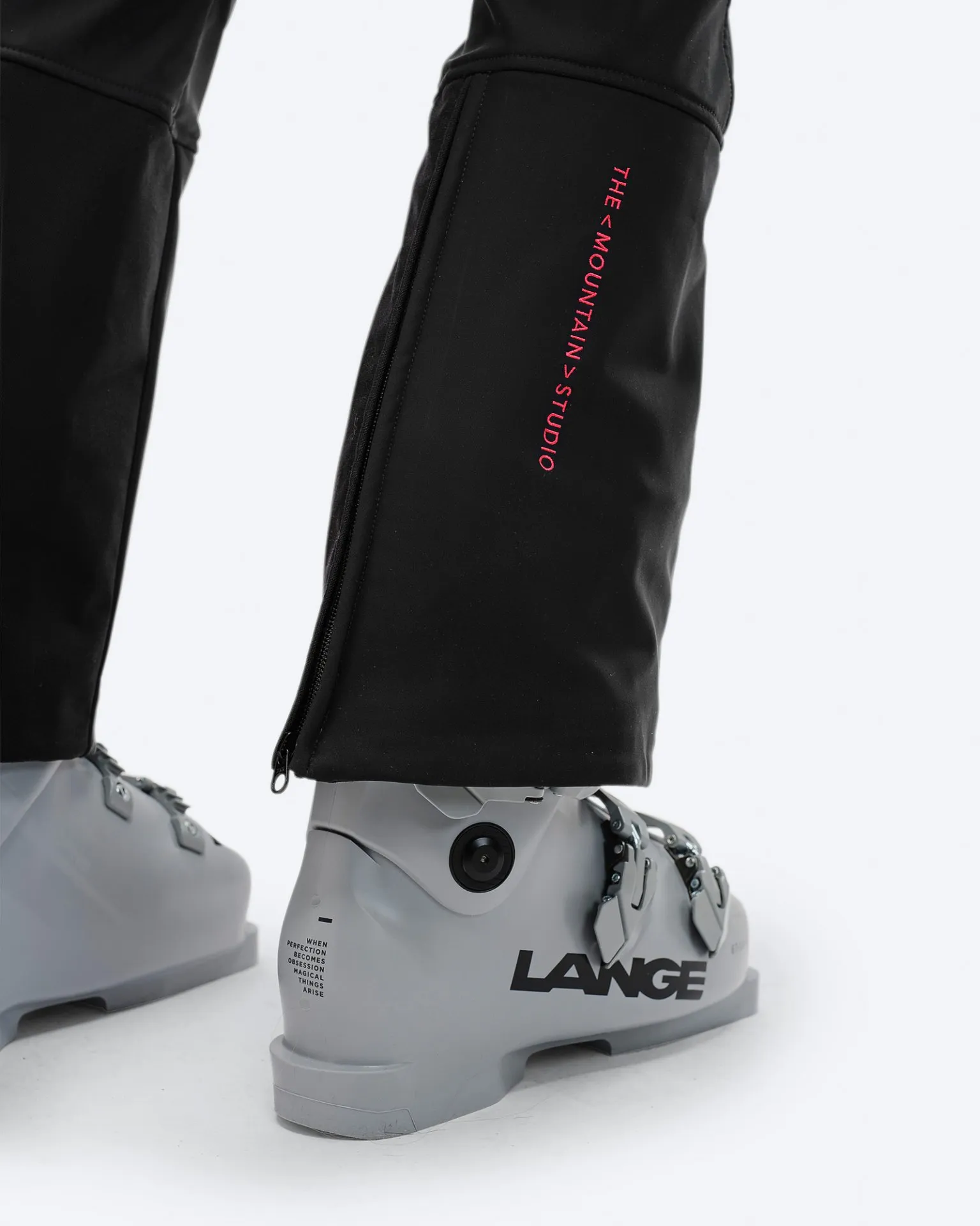 Detailaufnahme der schwarzen P-4 W 2L Stretch Ski Pants mit Ski-Schuh. Reißverschluss am Beinabschluss und Logo sichtbar.