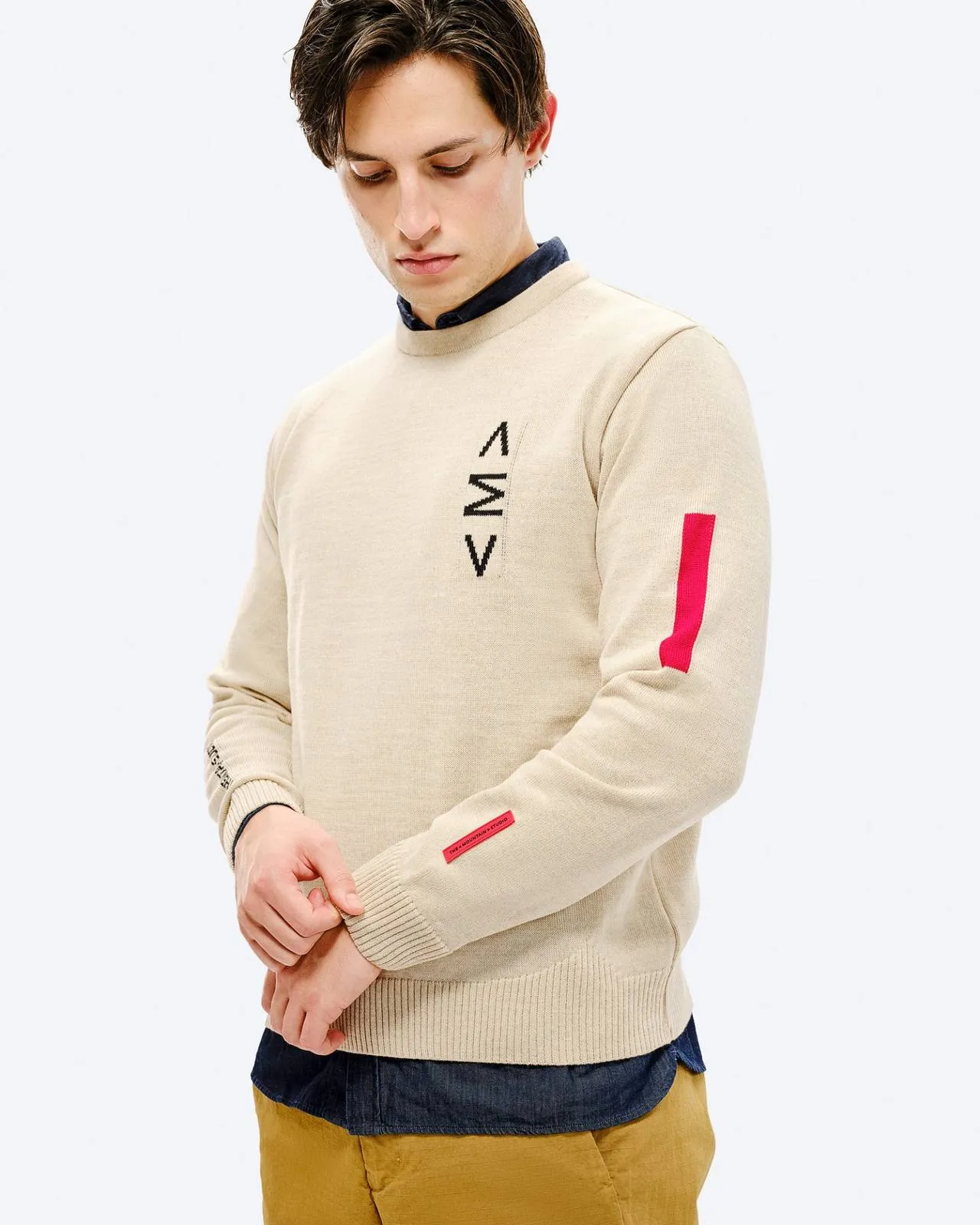 Uomo con maglione da sci St. Moritz. Maglione beige con dettaglio rosso sulla manica e motivo nero sul petto.