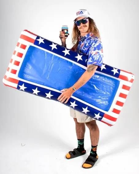 Uomo con occhiali da sole, berretto USA, motivo USA, che tiene in mano una lattina e un materassino da piscina con il disegno della bandiera USA.