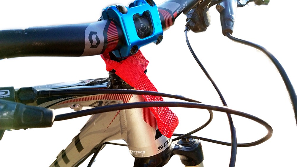 Nahaufnahme eines Fahrradlenkers mit montierter, roter Tow-Whee Quick Loop Schleife. Diese verbindet Lenker und Rahmen.