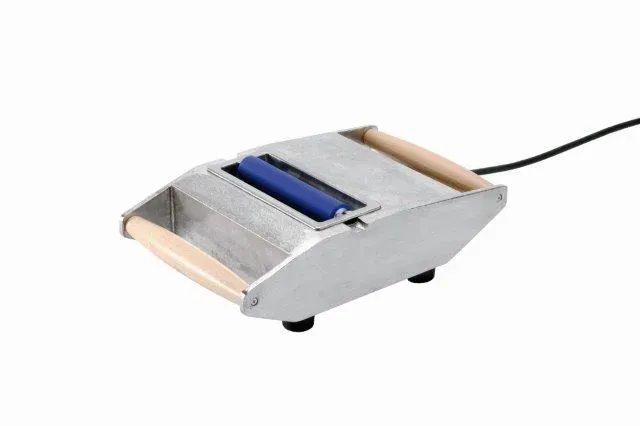 Silver, elongated hand-held device with rounded ends and two light brown wooden handles on the sides. In the center, a blue roll in an elongated slot. Black cord on the right. On four small black feet.