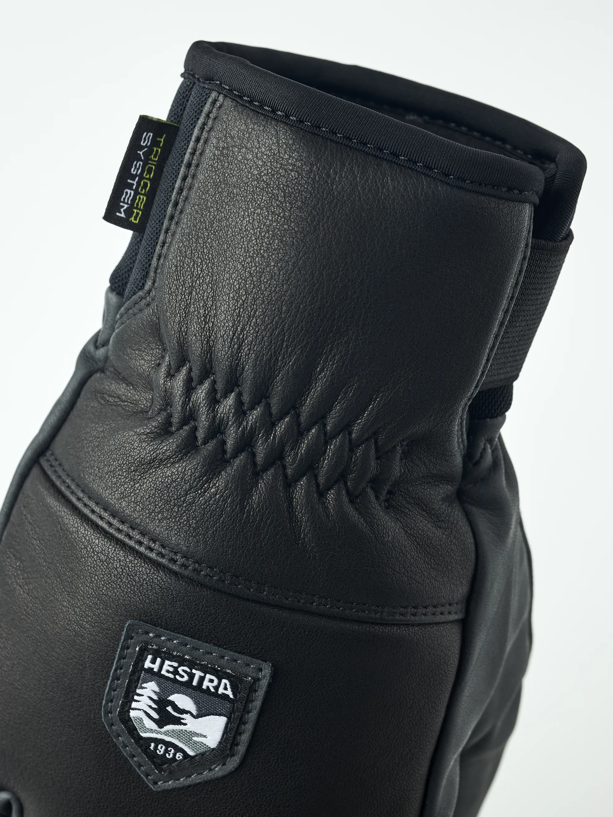 Primo piano di un guanto Hestra Omni Trigger in pelle nera con logo del marchio.